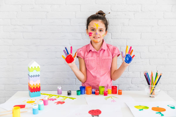 Cheerful little child having fun doing finger painting